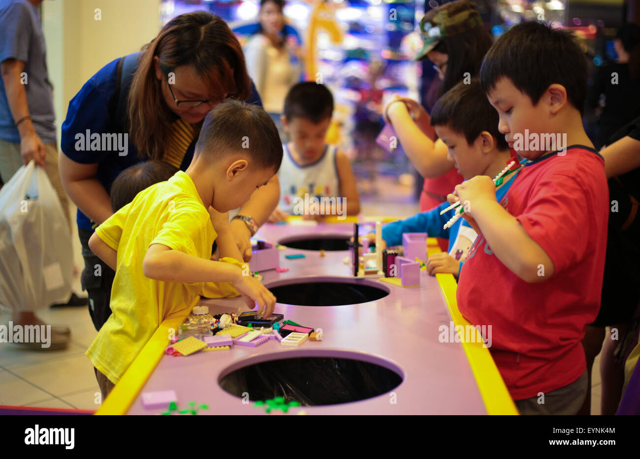 Parent accompanying their children playing at lego playtable. Stock Photo