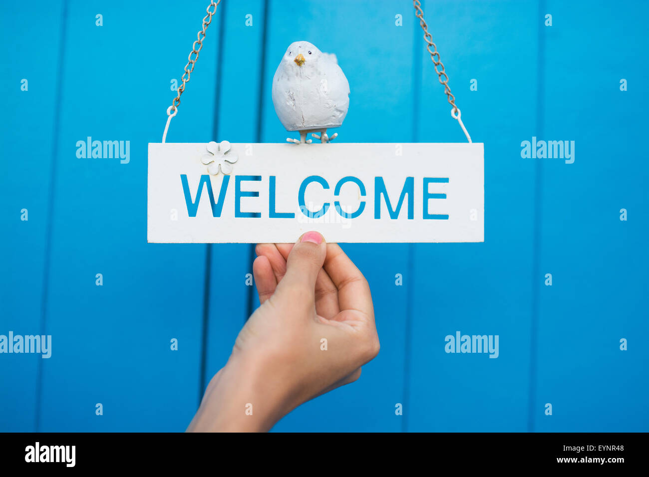 woman holding welcome sign on blue background Stock Photo