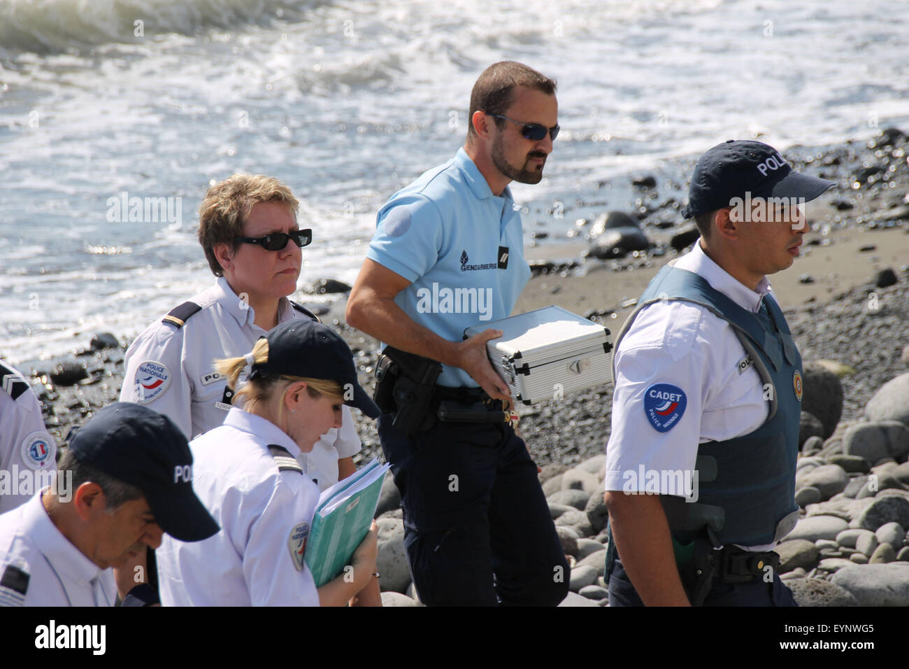 Saint Denis, Reunion. Aug. 2, 2015. Police officers leave the beach with a container holding metallic debris found on the island. A piece of metal was found on a beach near Saint-Denis. The flaperon discovered on Reunion Island has been officially identified as being part of a Boeing 777 aircraft, the same type of plane of the missing flight of Malaysia Airlines MH370. Credit:  Xinhua/Alamy Live News Stock Photo