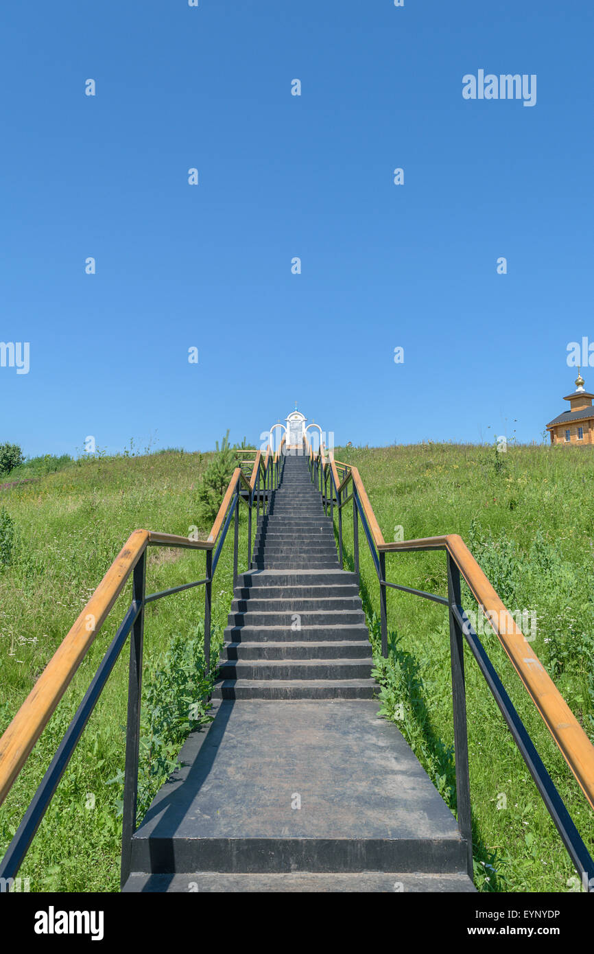 Metal stairs with railings leading up to the place of prayer and a wooden chapel on the hill. Stock Photo