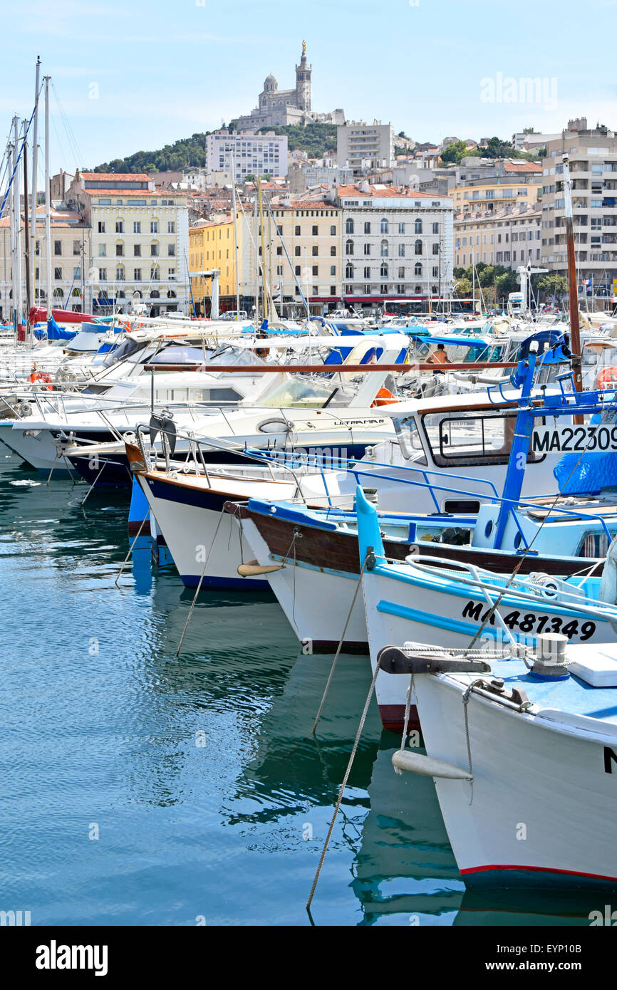 Marseille Vieux Port & French church of Notre Dame de la Garde on hilltop overlooking boats moored in The Old Port of Marseilles Mediterranean France Stock Photo