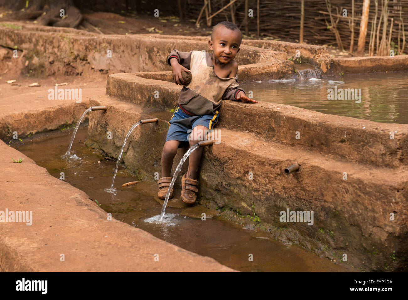 Boy sitting at a water fontain, part of irrigation scheme, Asossa, Ethiopia Stock Photo