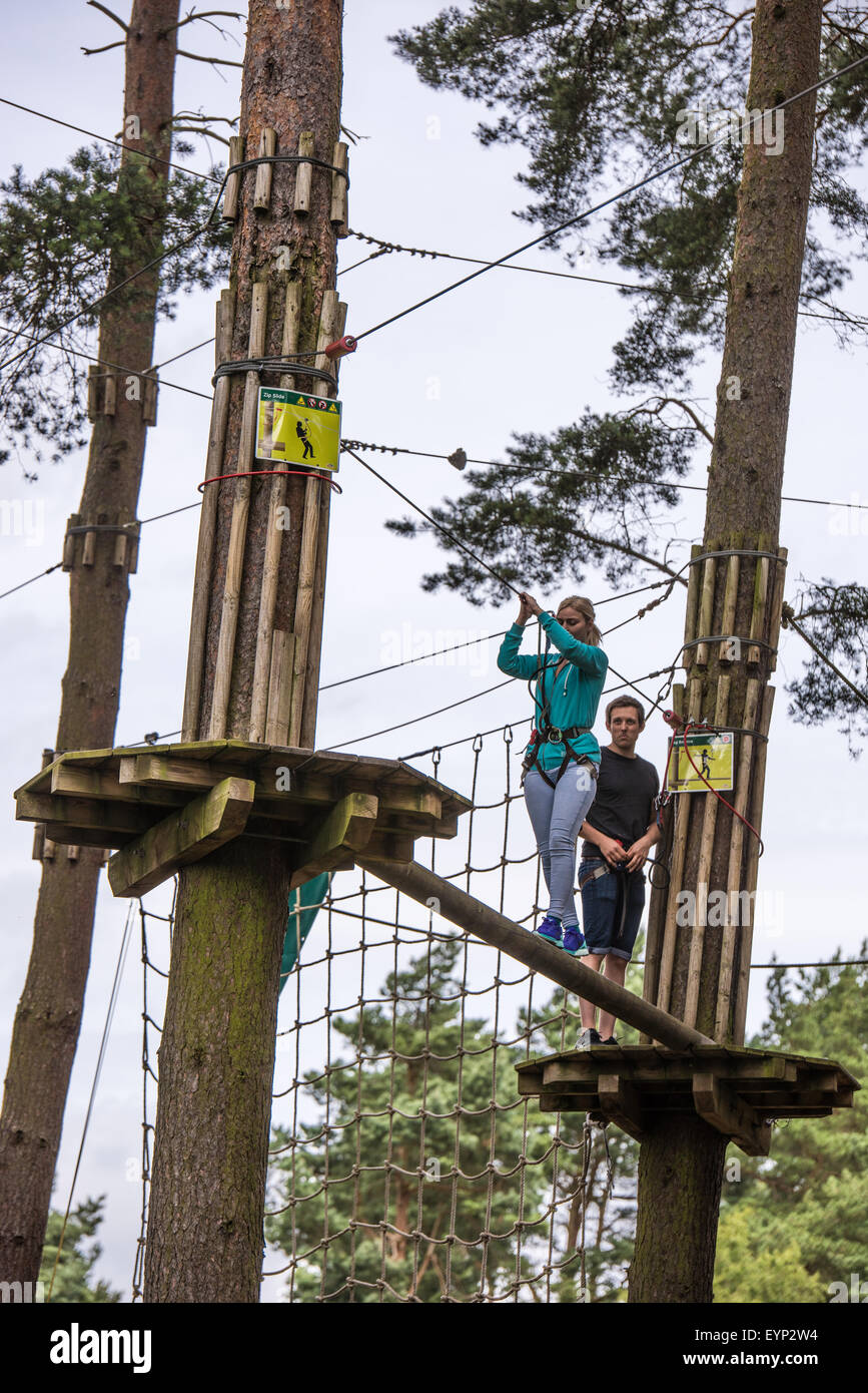 A girl on a high rope  in the tree tops at Go Ape Activity Centre , Cannock Chase Staffordshire West Midlands UK Stock Photo