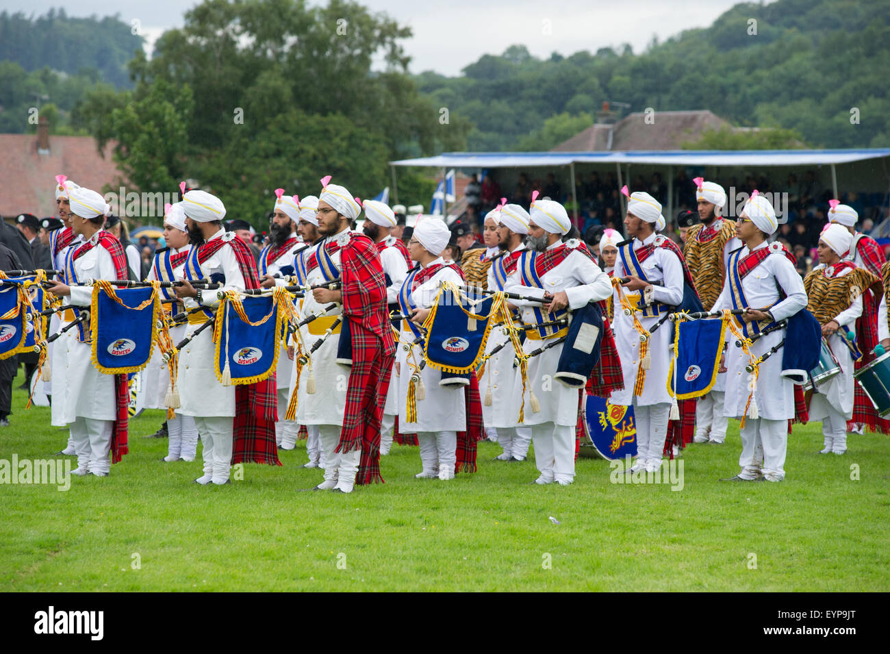 Bridge of Allan, Scotland, 2nd of August 2015. Bridge of Allan Highland Games 2015. Pipe bands, sporting and traditional Scottish competition events held in Bridge of Allan Highland near Stirling. The event is near the Ochil hills and has views of the Wallace Monument and the Stirling Castle. The Sri Dasmesh Malaysian Sikh Pipe band on the massed bands ready for prize giving. Credit:  Andrew Steven Graham/Alamy Live News Stock Photo