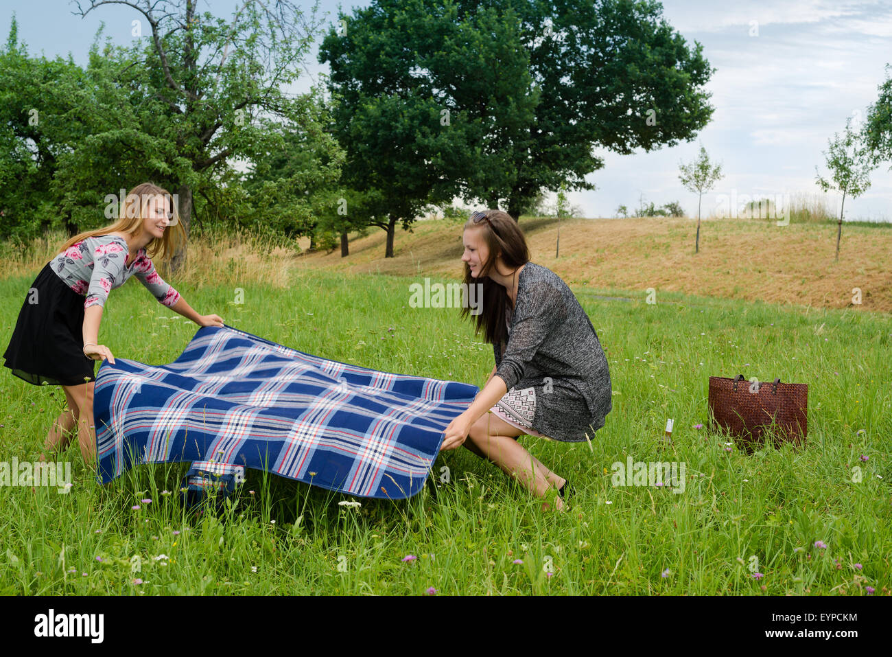 Two girls  spreading a blanket for picnic Stock Photo