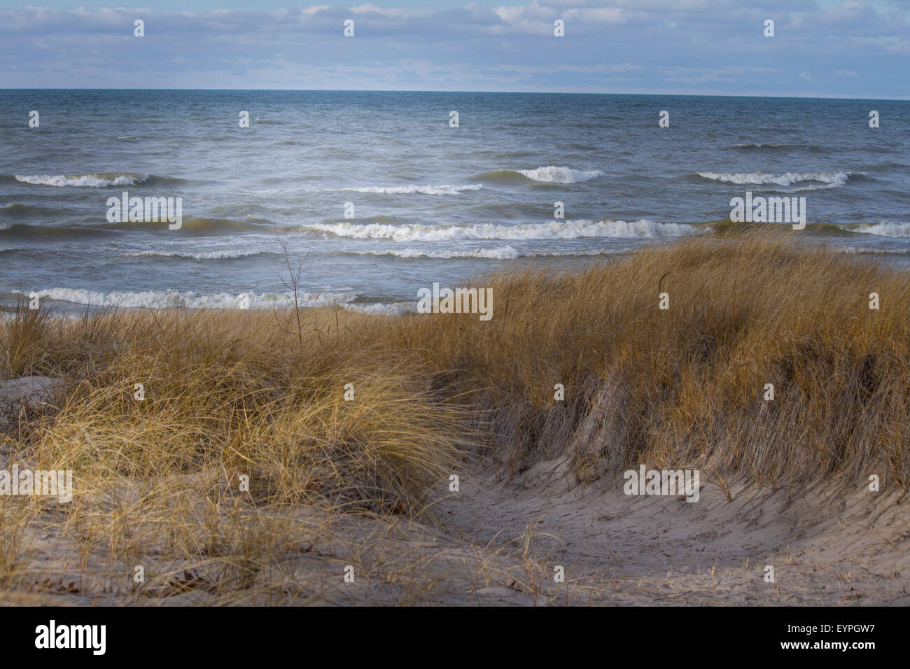 View of Lake Huron from beach of sand grass with light shining on the water Stock Photo