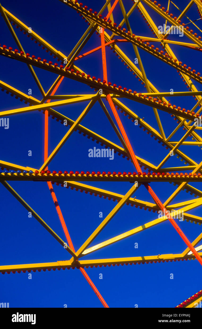 Details of red and yellow ferris wheel structure framed against saturated blue sky Stock Photo