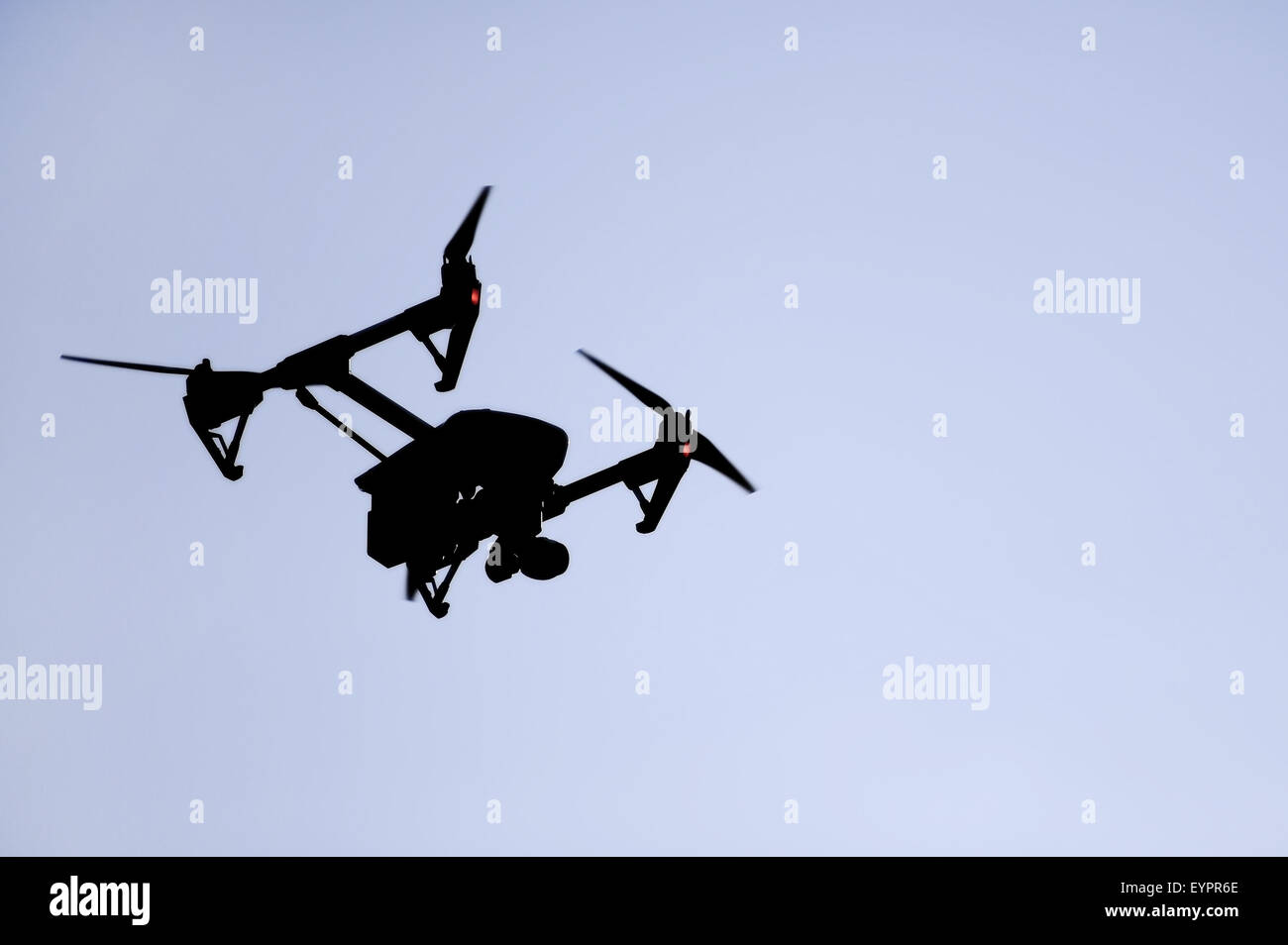 Aerial filming drone silhouetted against blue sky Stock Photo