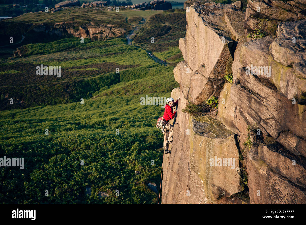 A climber climbing up ilkley Crags on Ilkley moor Stock Photo