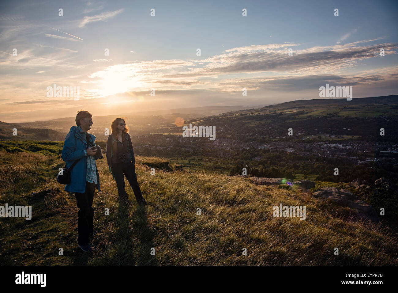Walkers / Photo Walkers taking in the view over Ilkley Moor at sunset Stock Photo