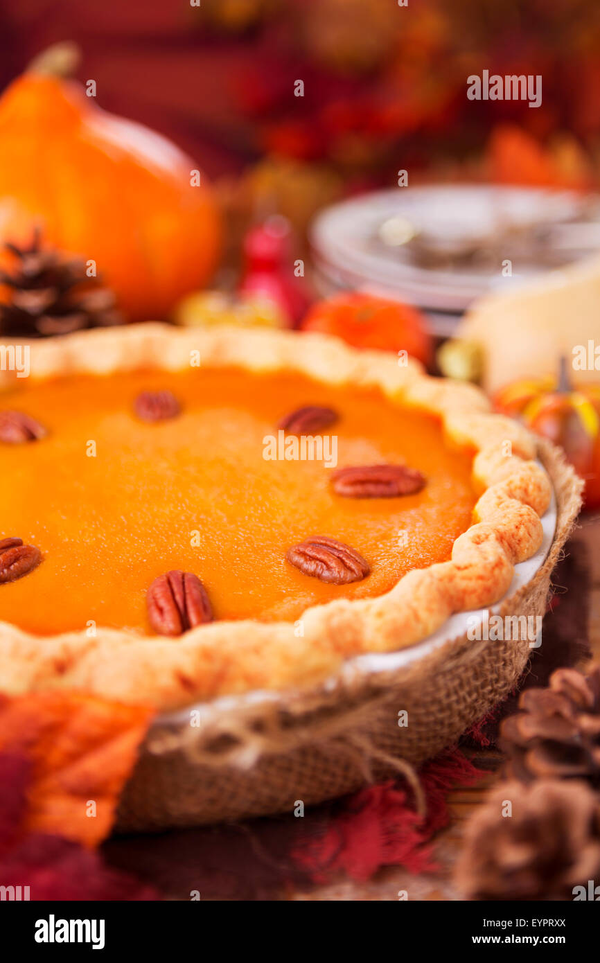 Homemade pumpkin pie on a rustic table with autumn decorations. Stock Photo