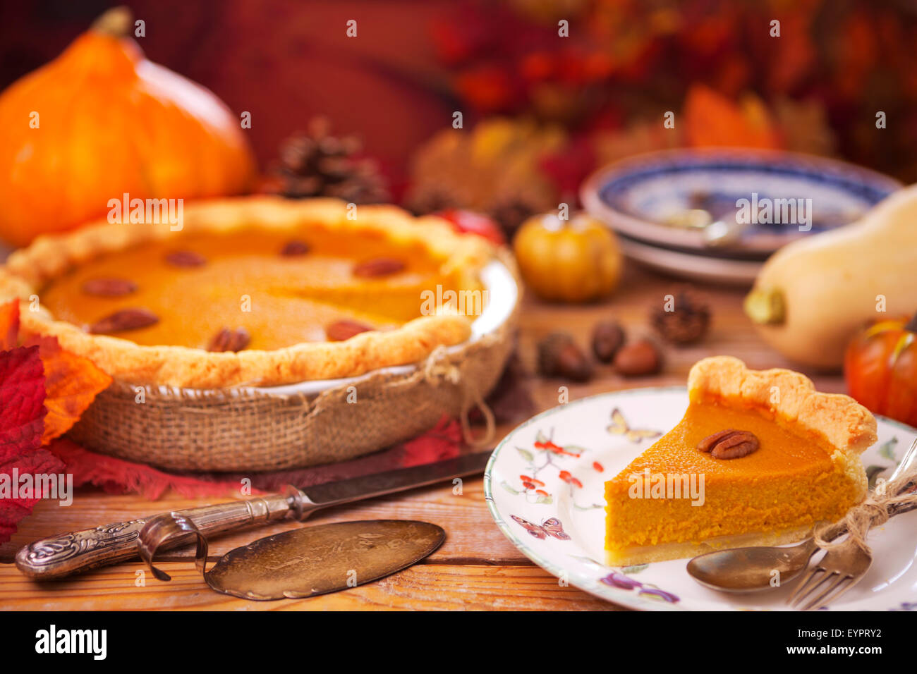 Homemade pumpkin pie on a rustic table with autumn decorations. Stock Photo