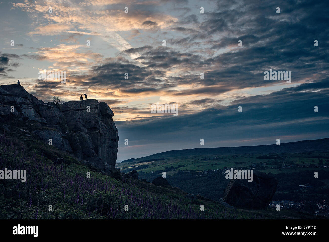 Climbers silhouetted on top of cow and calf rock, Ilkley Moor at sunset Stock Photo