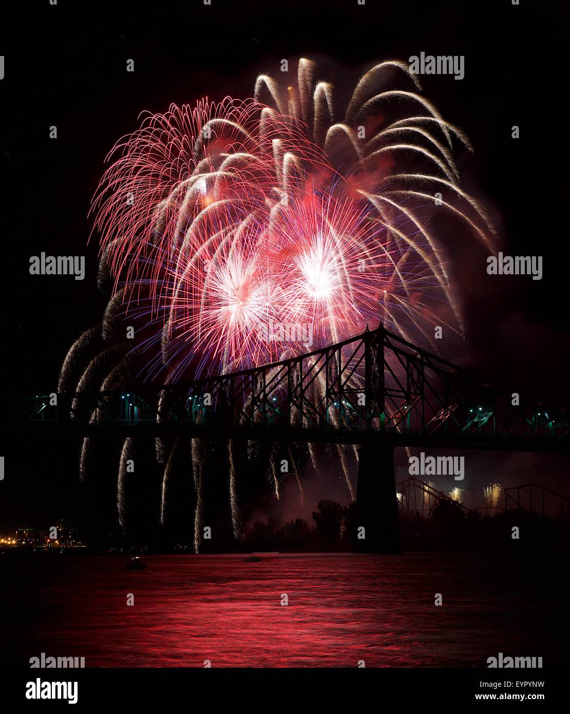Red fireworks explode in Montreal with bridge silhoutte in dark sky,Montreal fireworks festival, fireworks explode, New Year, fi Stock Photo