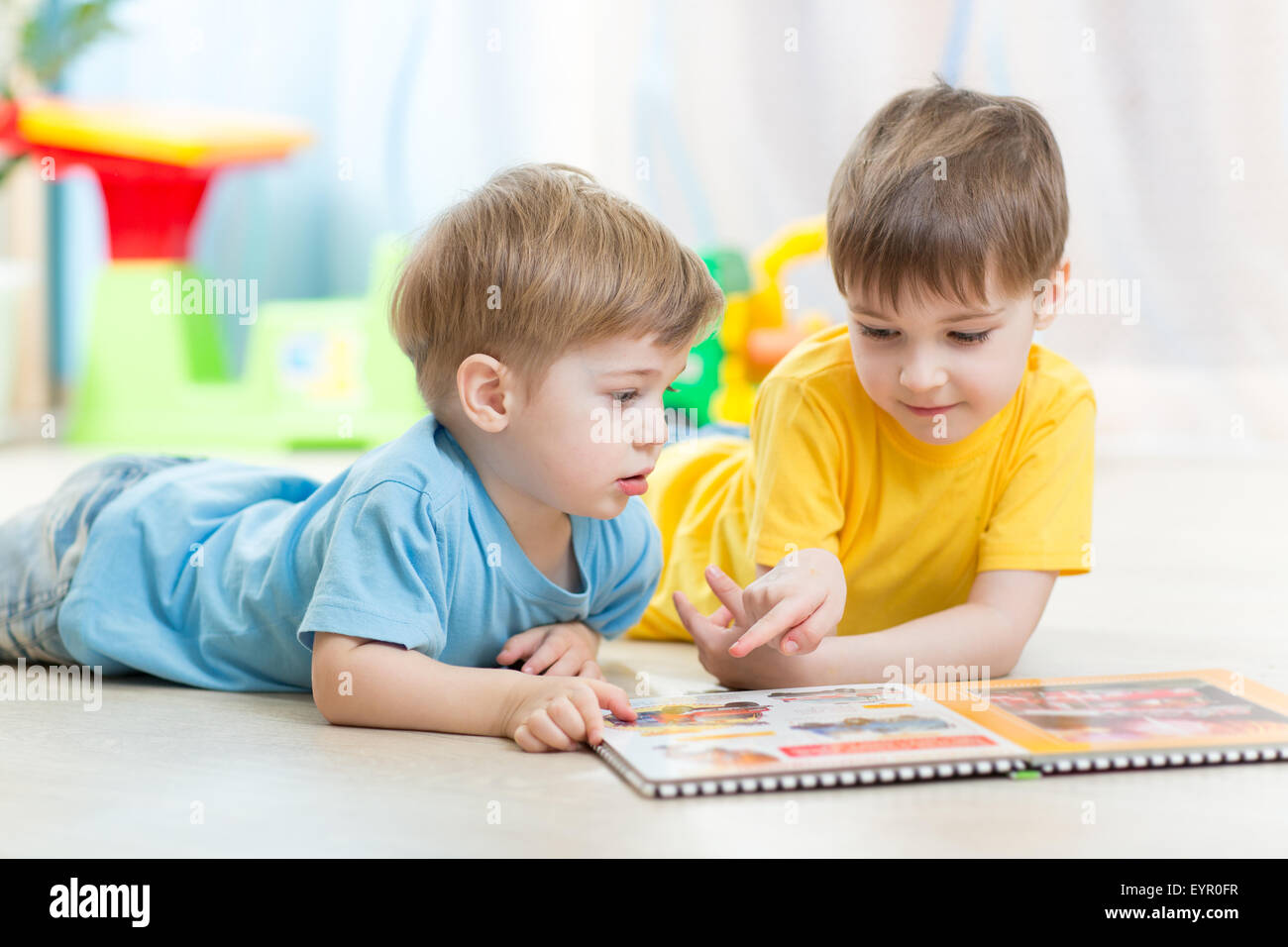 Kids looking at book in playschool or nursery Stock Photo