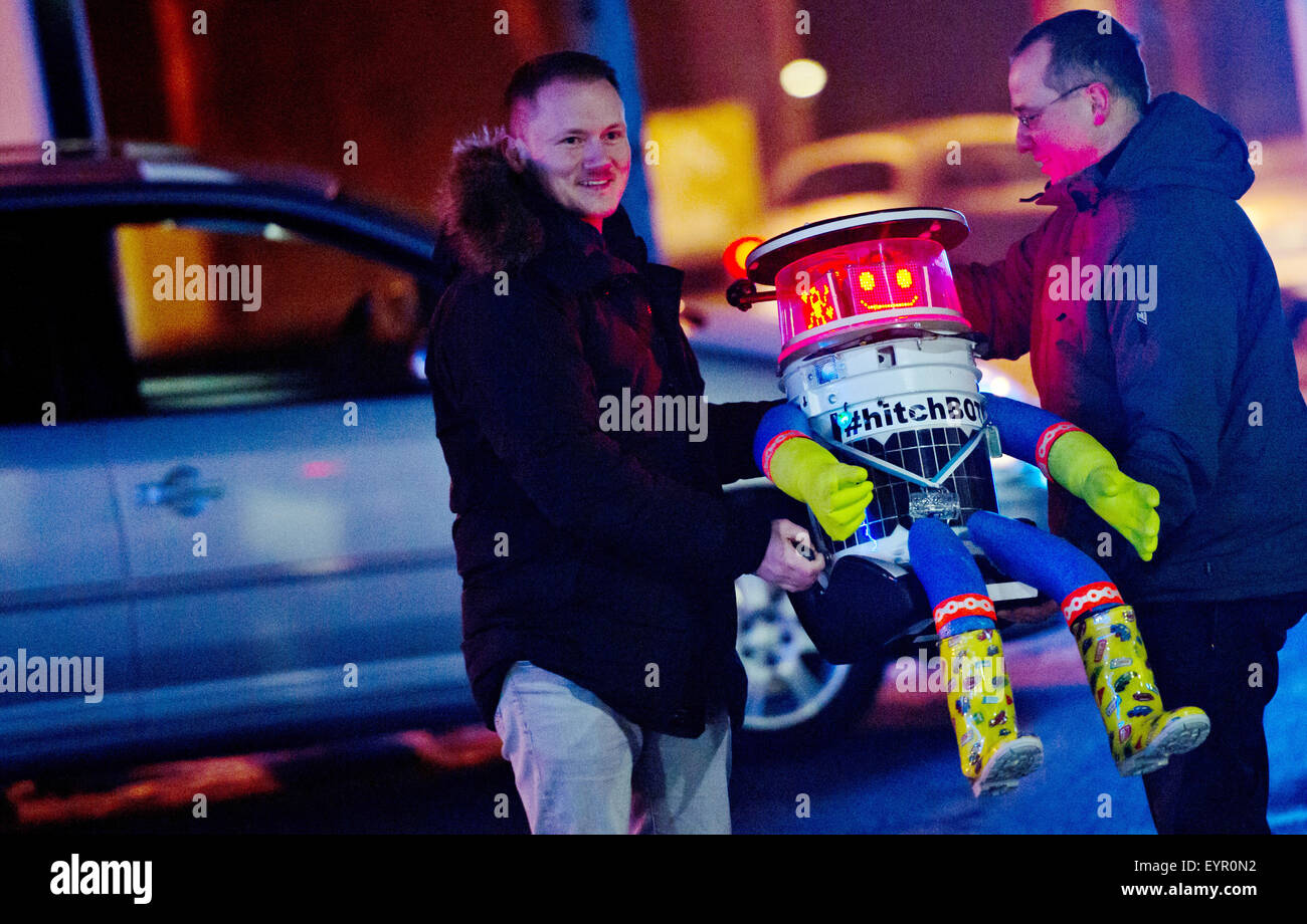 Munich, Germany. 13th Feb, 2015. The 'hitchBOT' robot is loaded into the car by Martin (L) and Bernd, who are taking the robot on his first leg, in Munich, Germany, 13 February 2015. 'hitchBOT' hitchhiked 6,000km through Canada over the summer and now begins a 10-day journey through Germany, starting in Munich. His first stop is the Neuschwanstein castle in Schwangau. Photo: Sven Hoppe/dpa/Alamy Live News Stock Photo