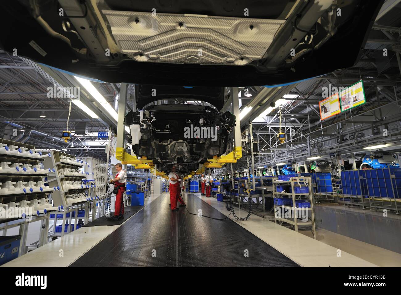 Inside a modern car factory, vehicles and parts move through the production process, under the suspended car bodies Stock Photo