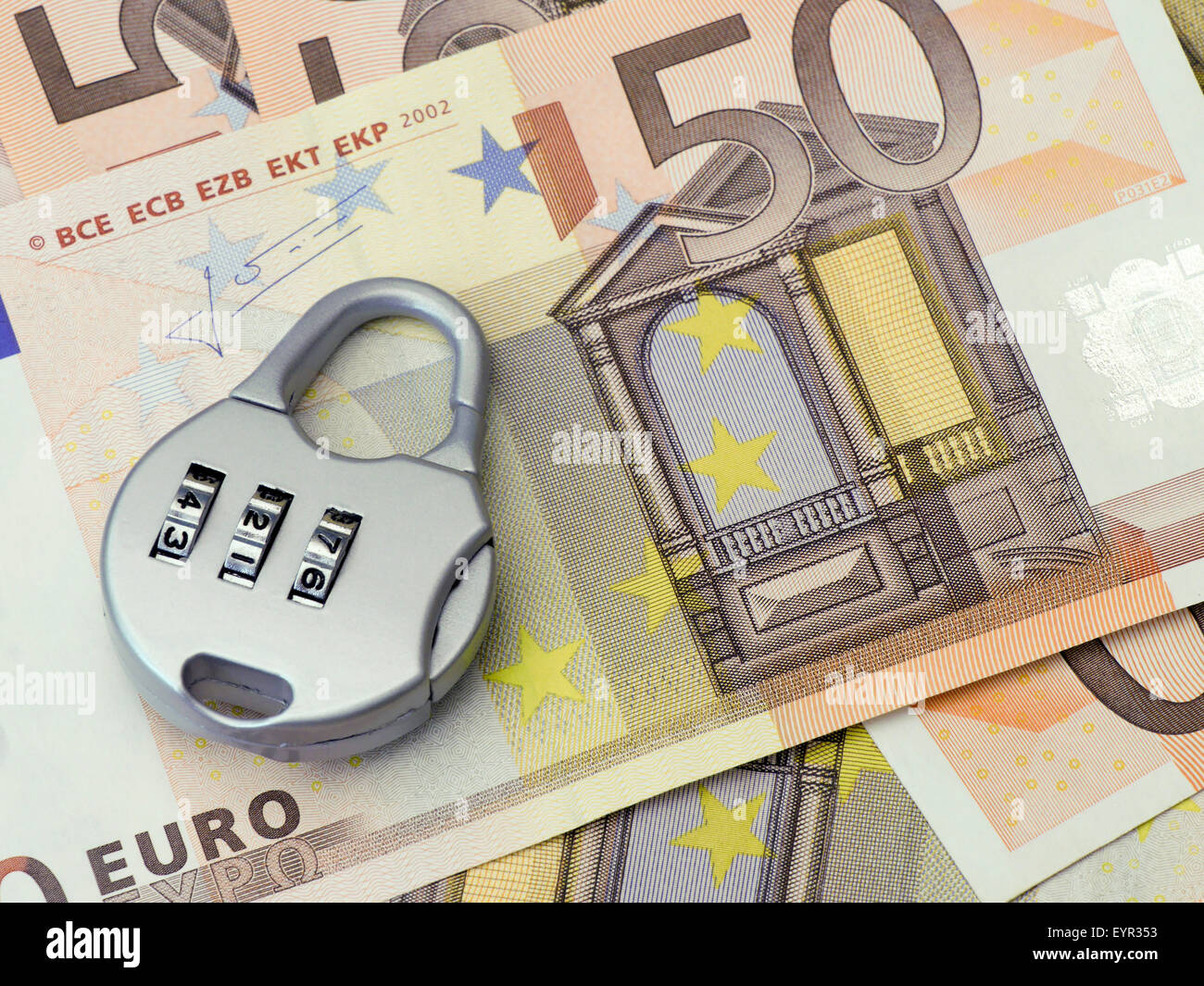 Combination padlock rests on Fifty Euro banknotes Stock Photo