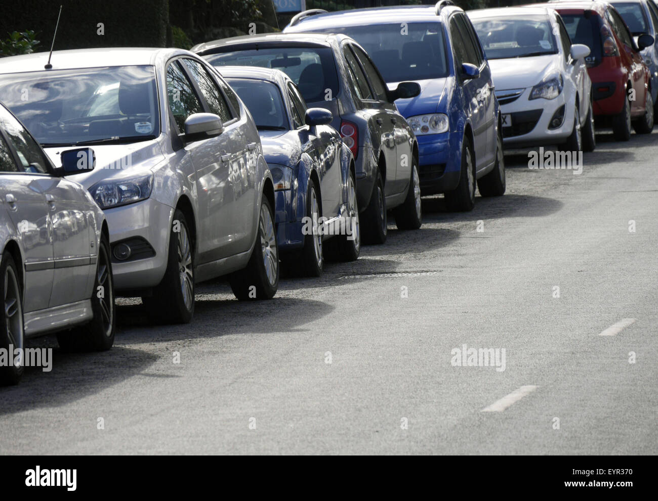 Long row of cars parked on city centre road Stock Photo