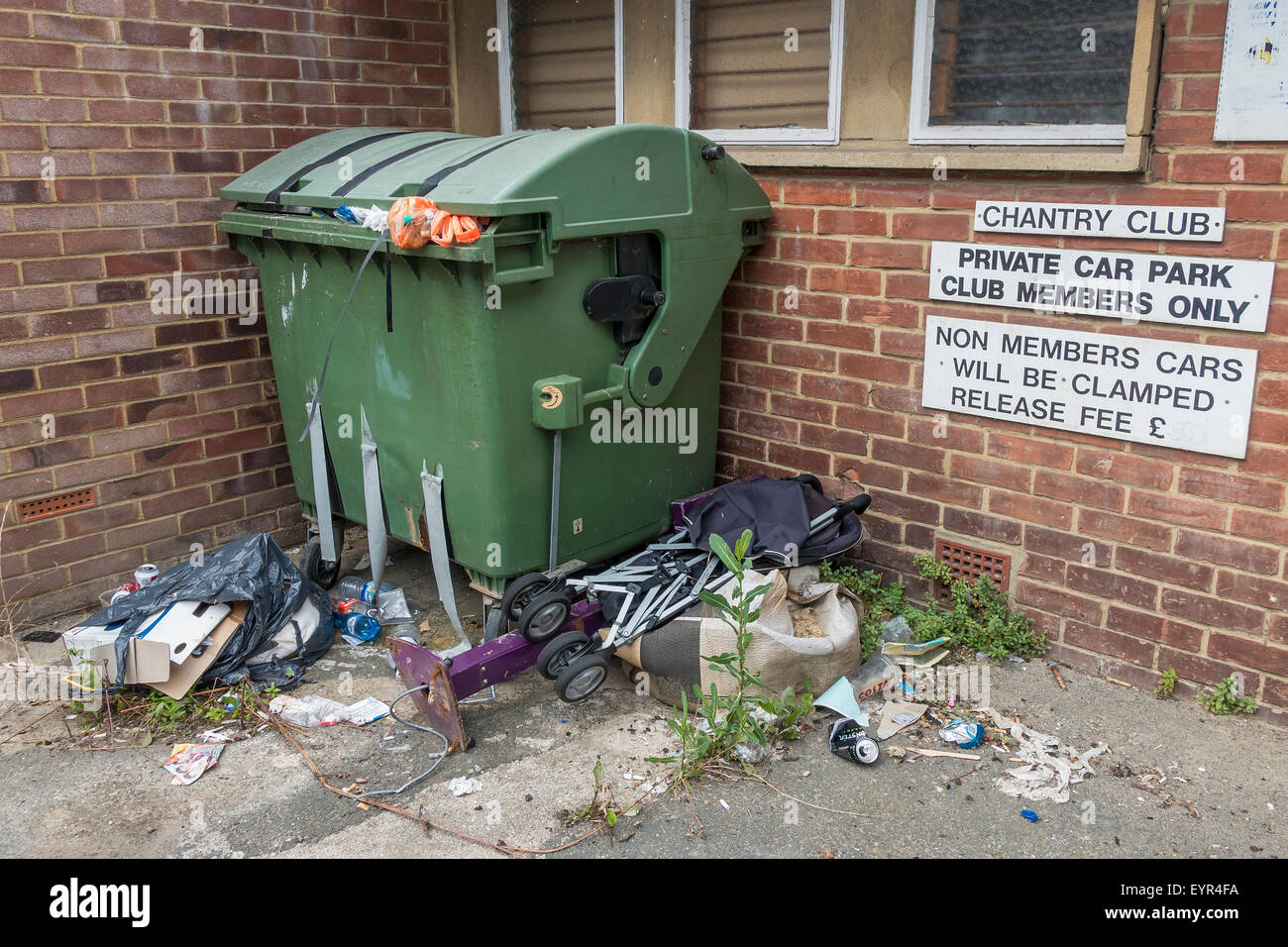 Overflowing rubbish dumped outside wheelie bin Stock Photo