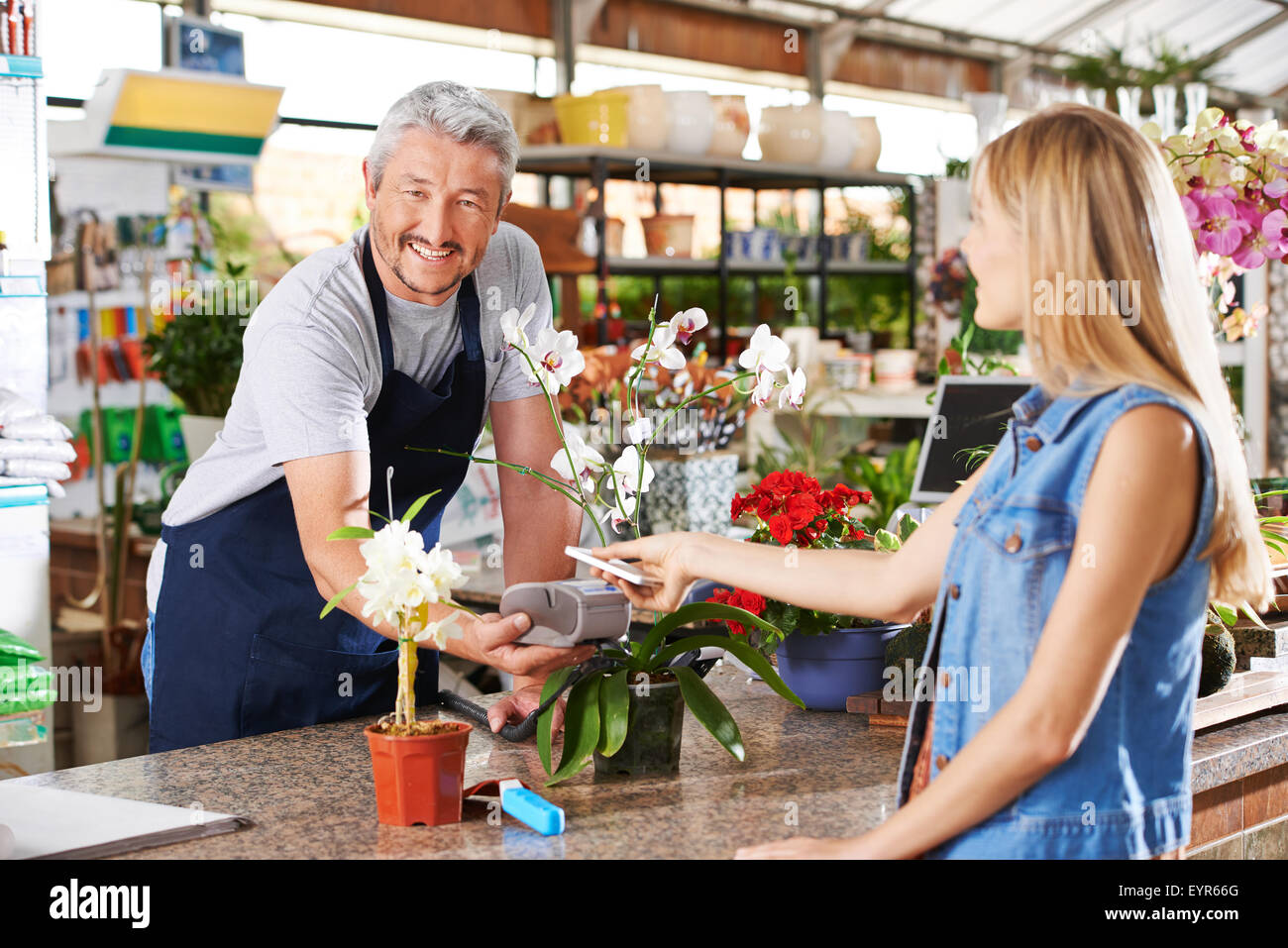 Mobile payment in garden center with salesman and customer Stock Photo