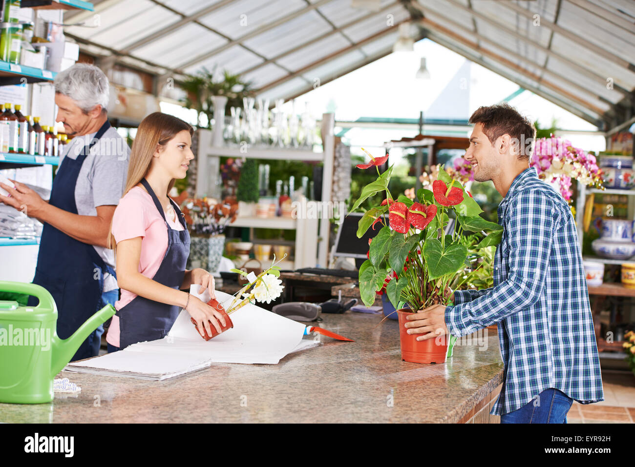 Man as customer in nursery shop talking to woman at checkout Stock Photo