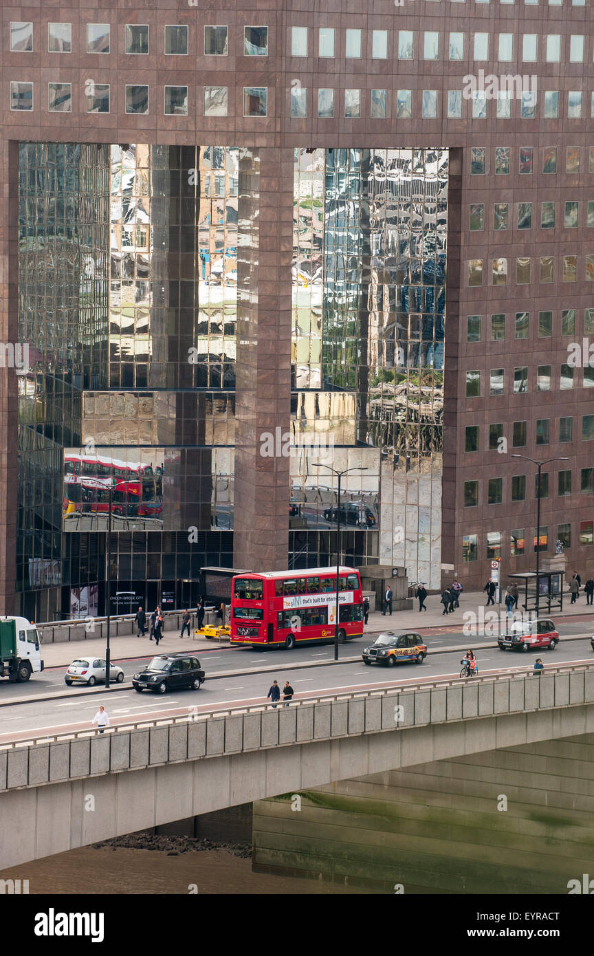 London, England. No 1 London Bridge with red bus and black cabs, reflection in modern mirrored building. Stock Photo