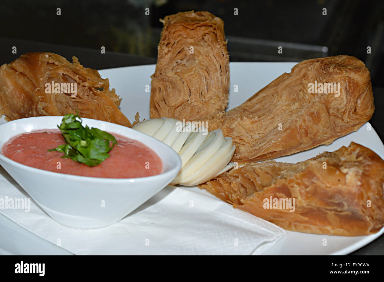 Jachnun with tomato, hard boild egg and Skhug a spicy dip. Jachnun is a traditional Yemenite