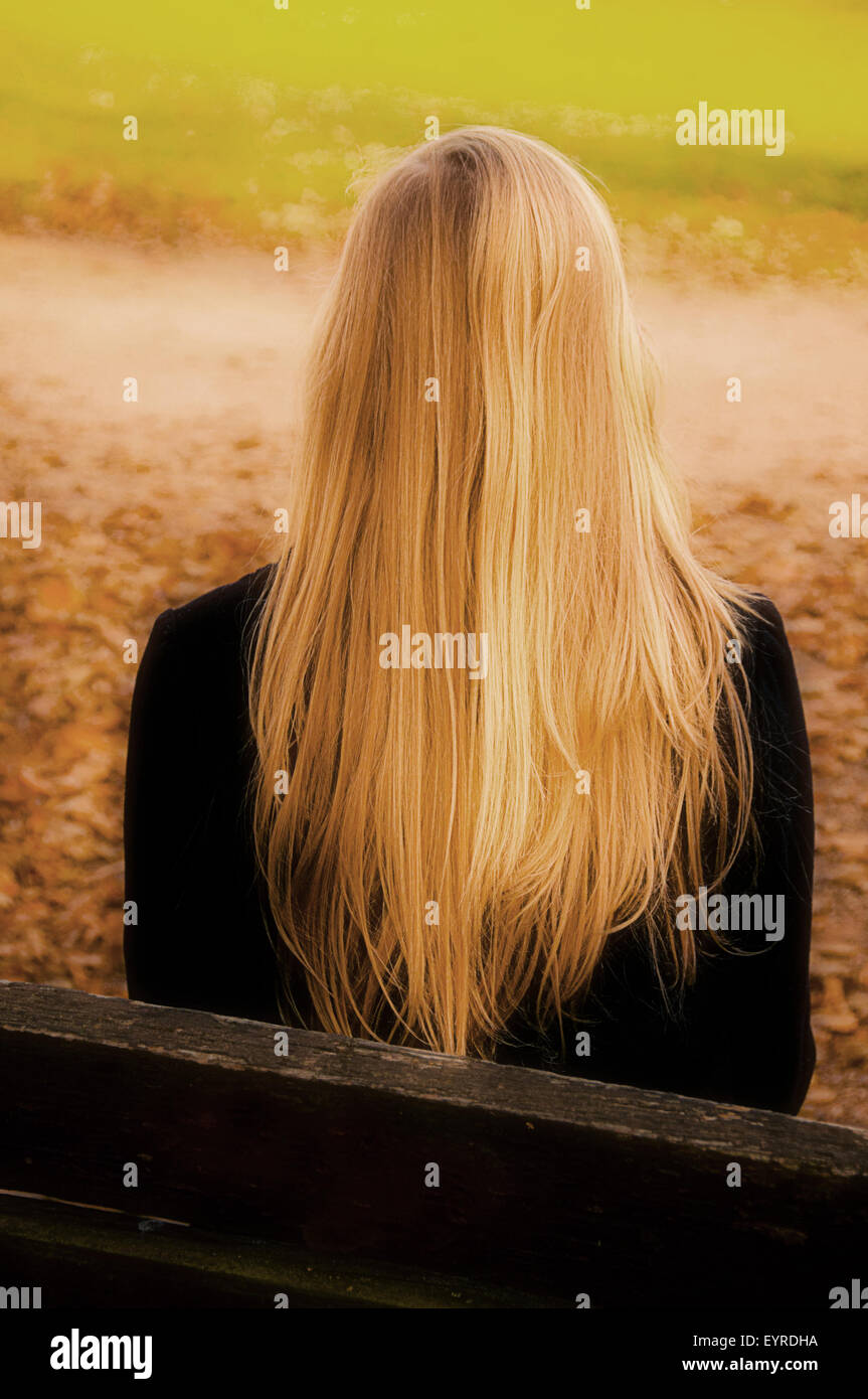 Young Woman With Long Straight Hair Sitting On A Bench Back View