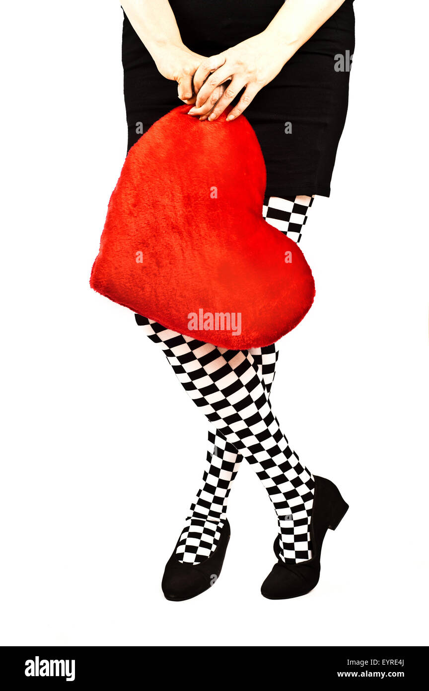 legs of a woman in checkered socks and a red heart shaped cushion Stock Photo