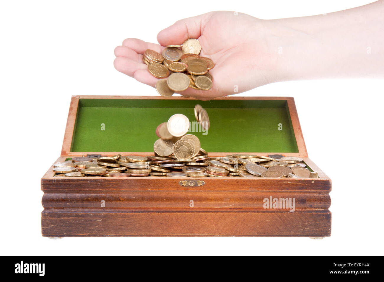 Hand dropping coins in a treasure chest Stock Photo