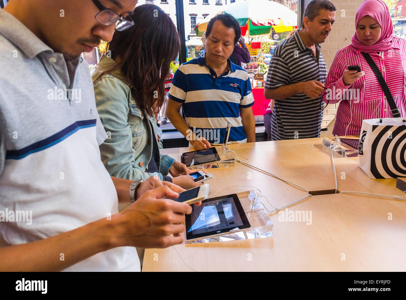 New York City, USA, Group People using new exciting technology store. Apple Store in Manhattan, Trying new equipment, Iphones, apple showroom, looking at phones store, apple boutique, diverse america, buying tech products 'Big Tech » phones store Stock Photo