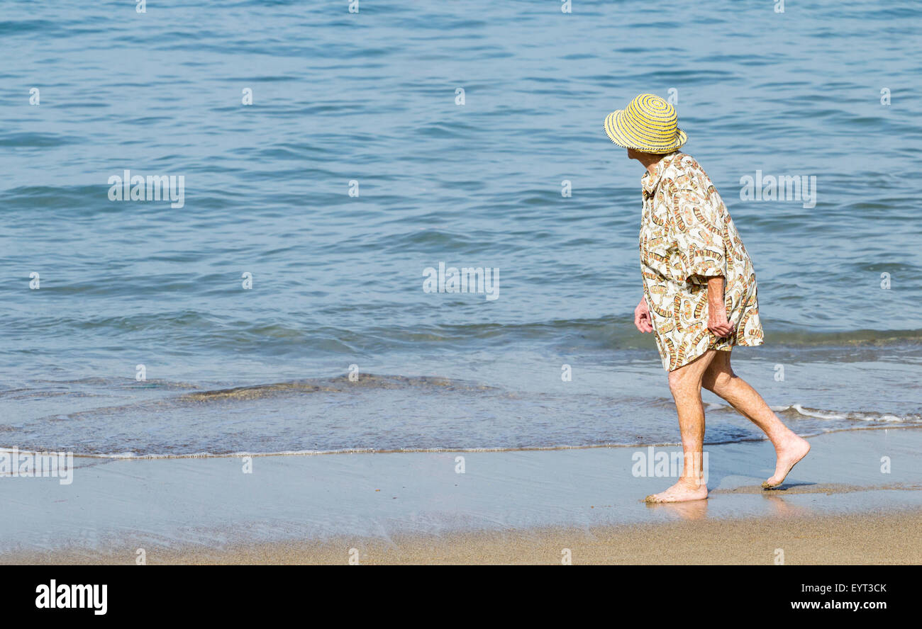 Elderly woman walking on beach Stock Photo