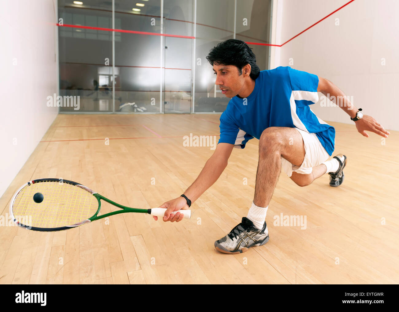 Squash player hiting a drop shot in a squash court Stock Photo - Alamy