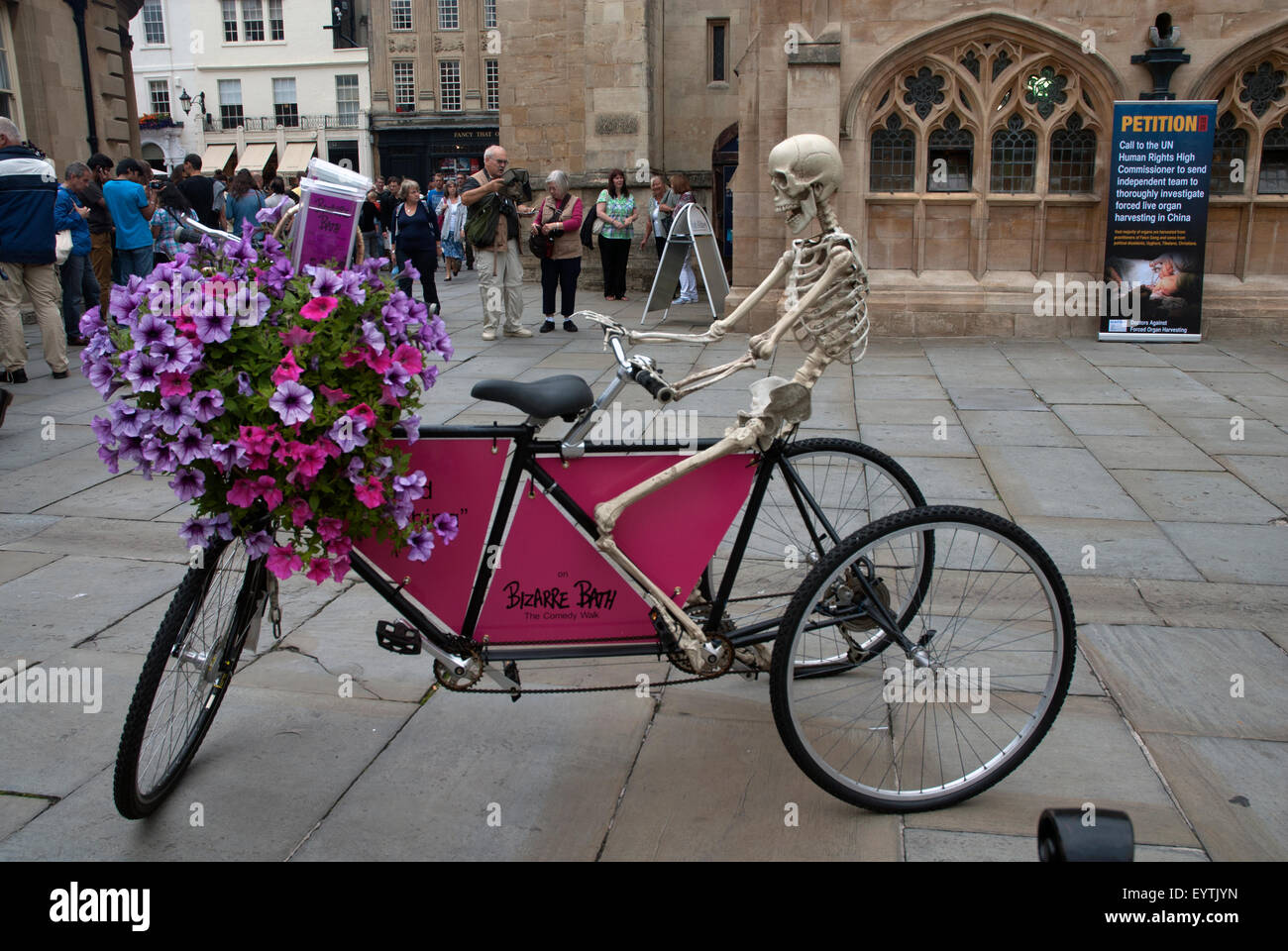 Skeleton on a bicycle advertising Bizarre Bath walking tours, Abbey Churchyard Bath Spa, Somerset England UK Stock Photo