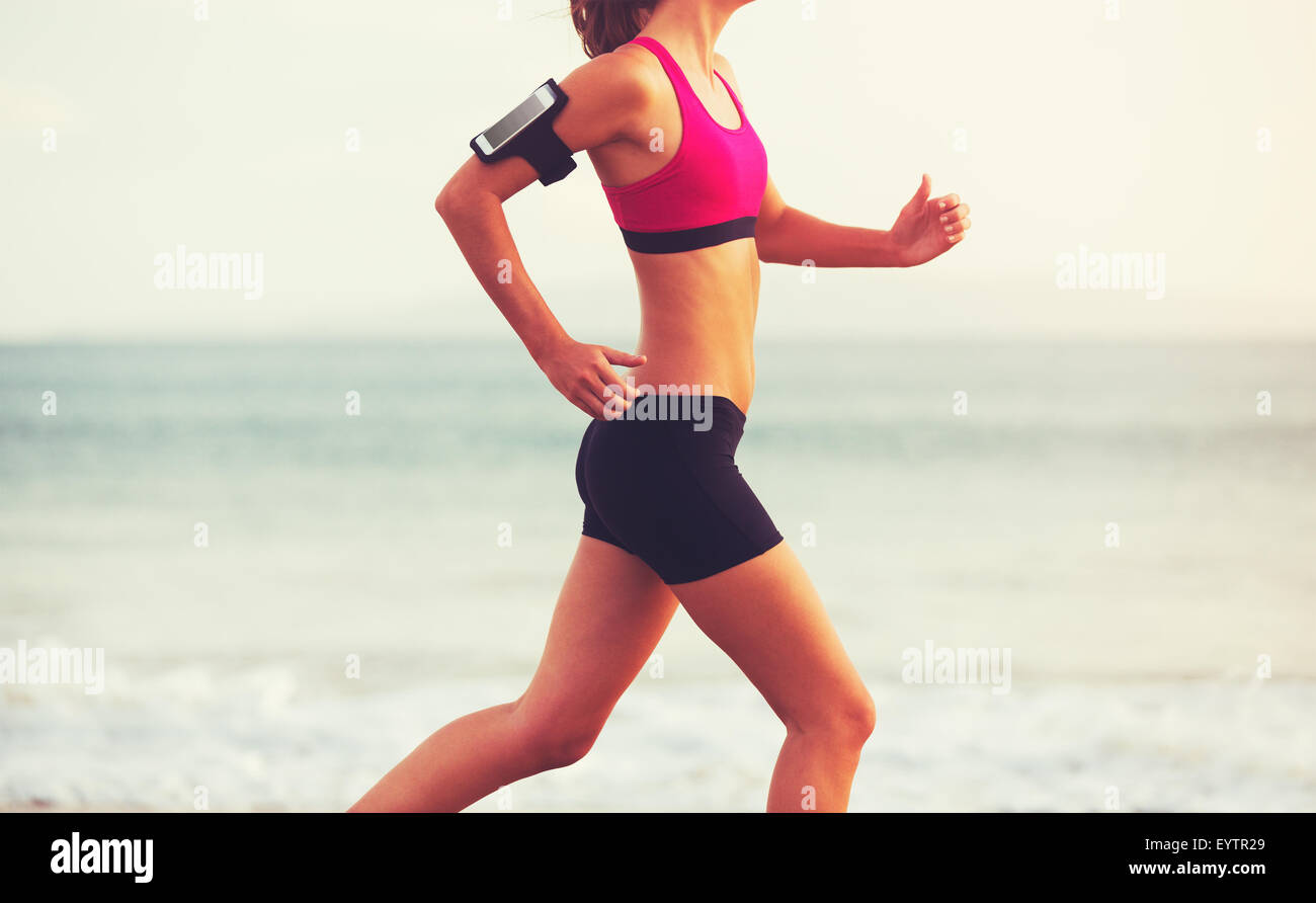 Healthy Active Lifestyle. Young sports fitness woman running on the beach at sunset. Stock Photo