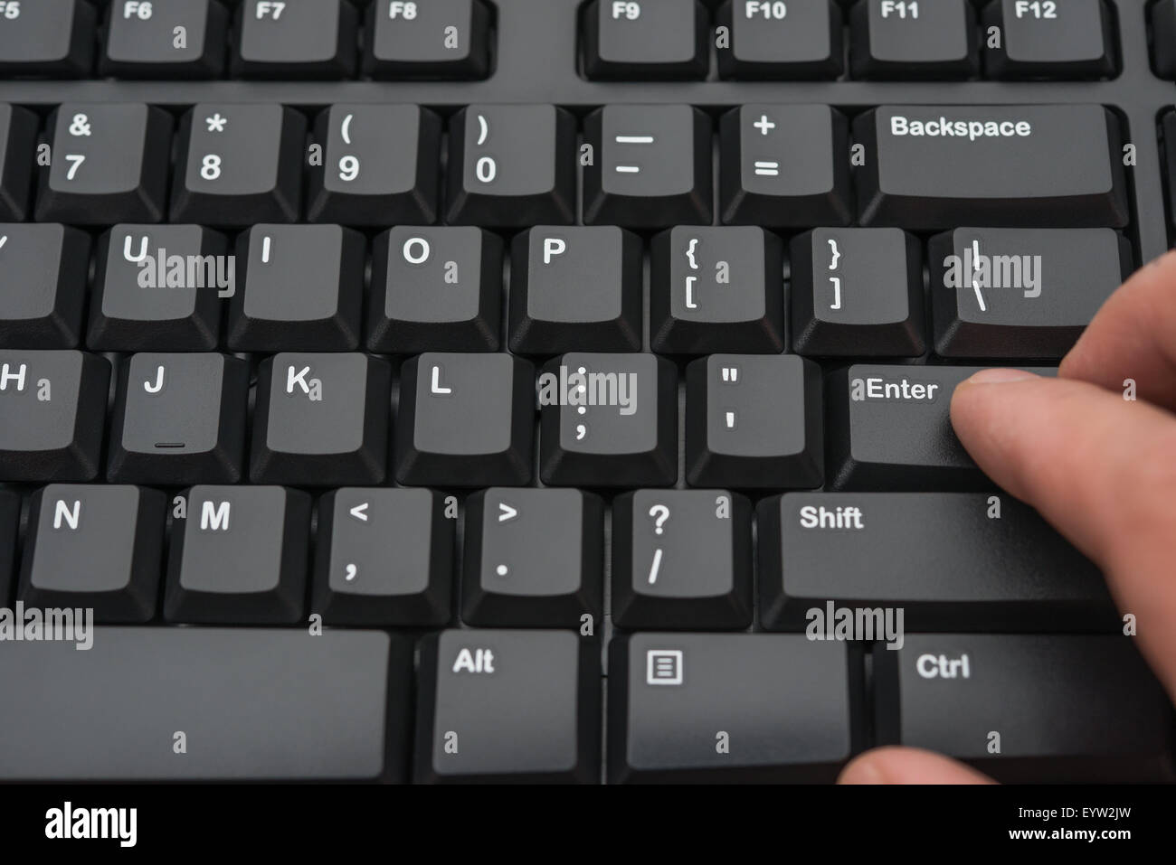 hitting the enter key of a black keyboard Stock Photo