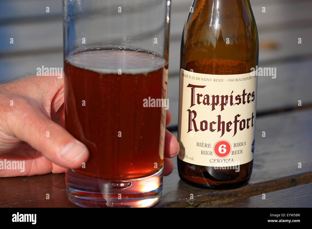 Hand of a man lifting a glass of Belgian beer Trappistes Rochefort Stock Photo