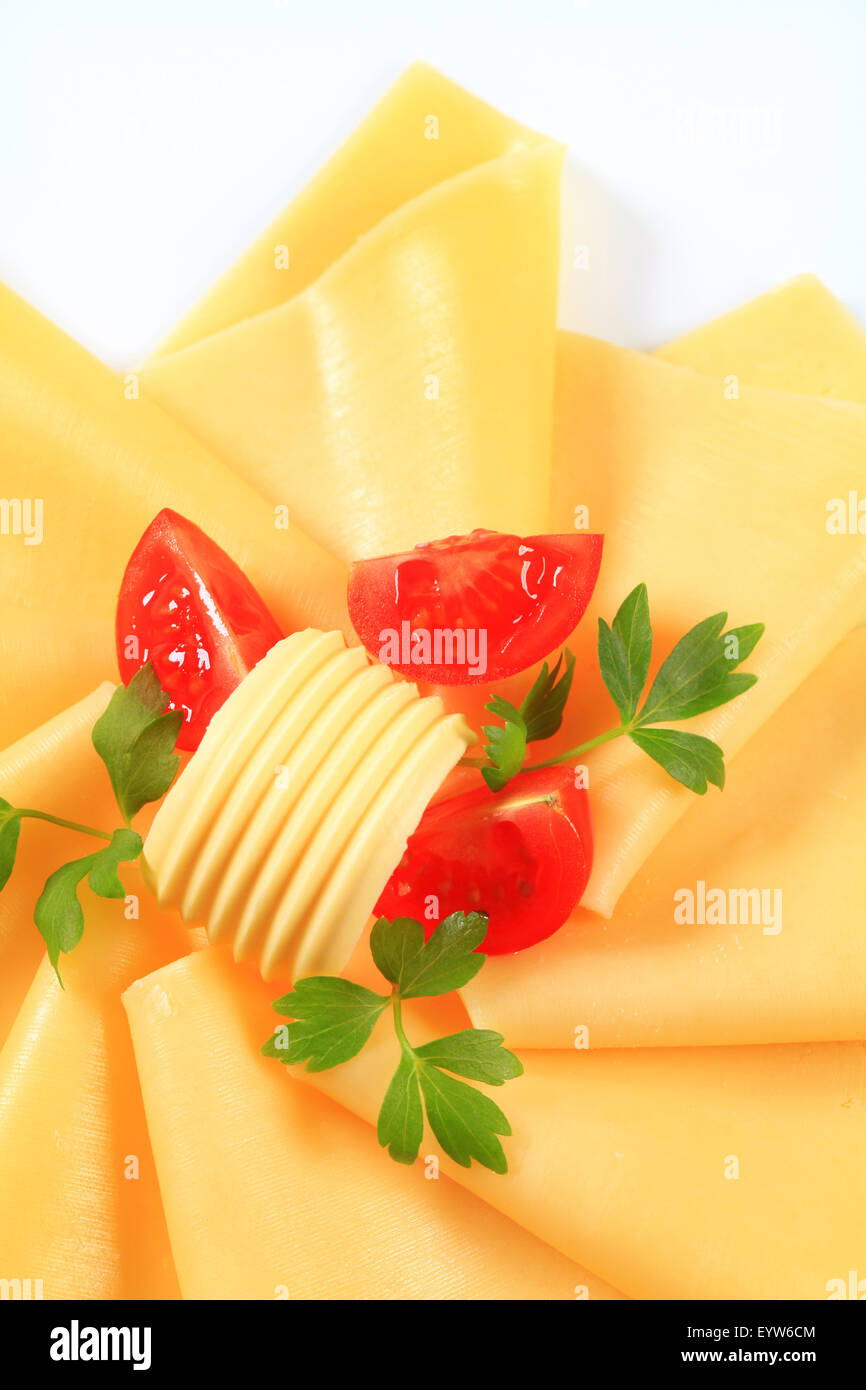 Thin slices of yellow cheese, butter curl and tomato wedges Stock Photo