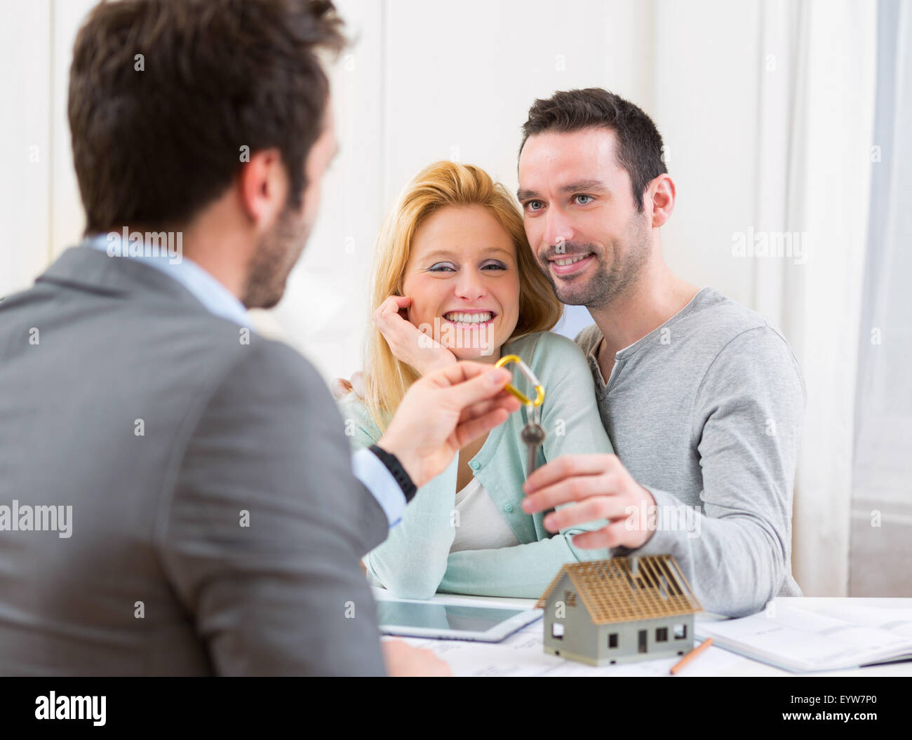 View of a Real estate agent delivers keys of new house to young couple ...