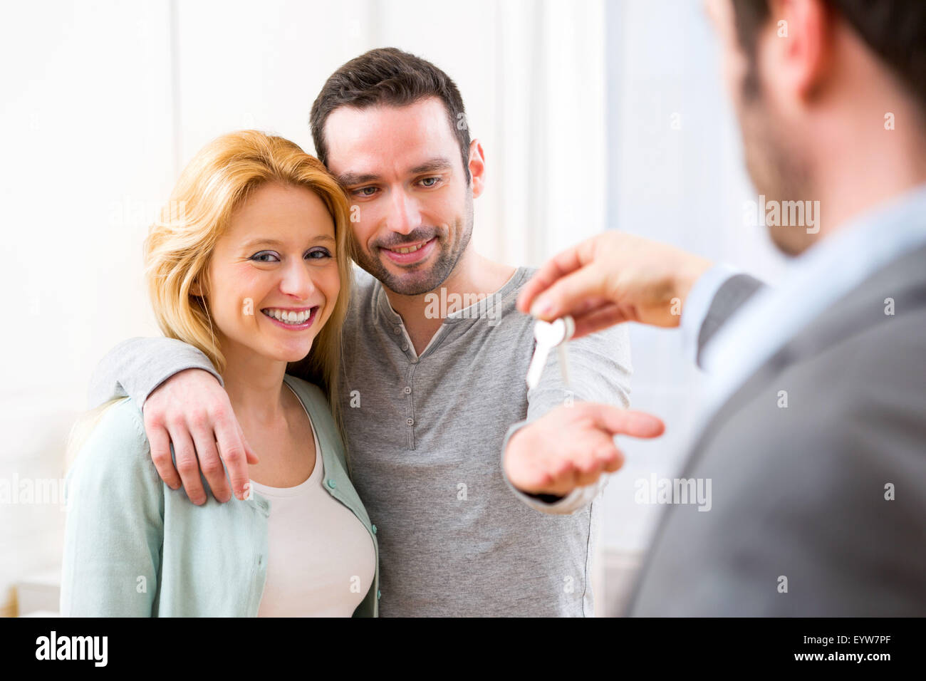 View of Real estate agent delivers keys of new house to young couple ...
