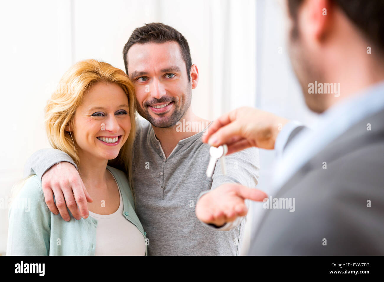 View of Real estate agent delivers keys of new house to young couple ...