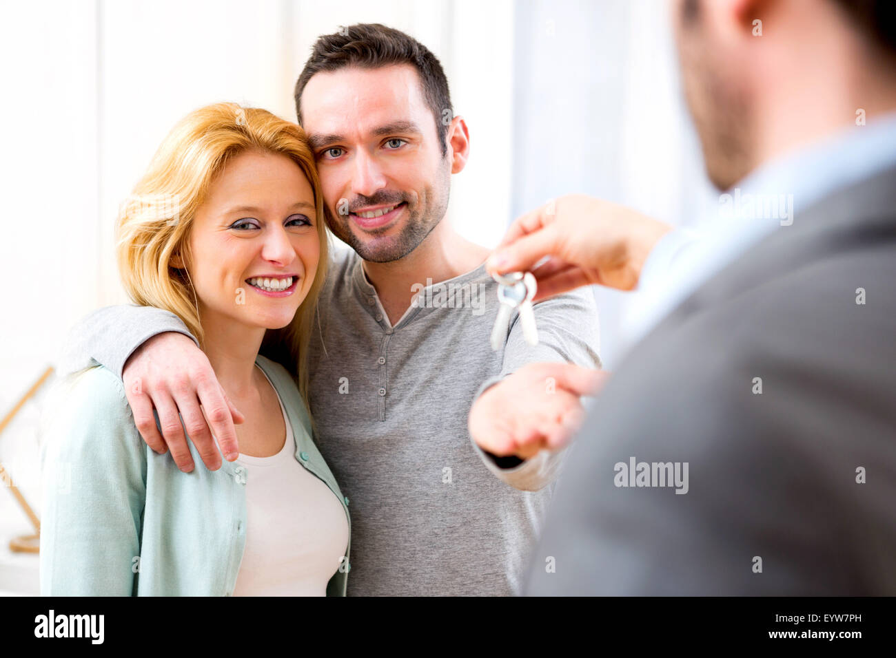View of Real estate agent delivers keys of new house to young couple ...