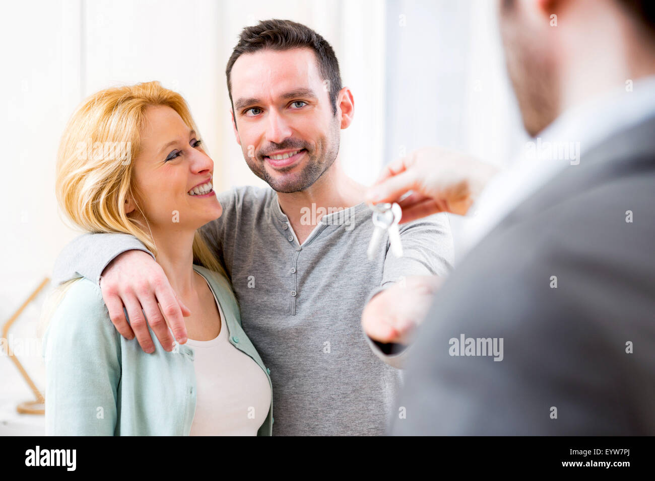 View of Real estate agent delivers keys of new house to young couple ...