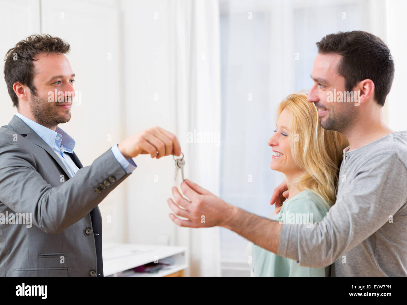 View of Real estate agent delivers keys of new house to young couple ...