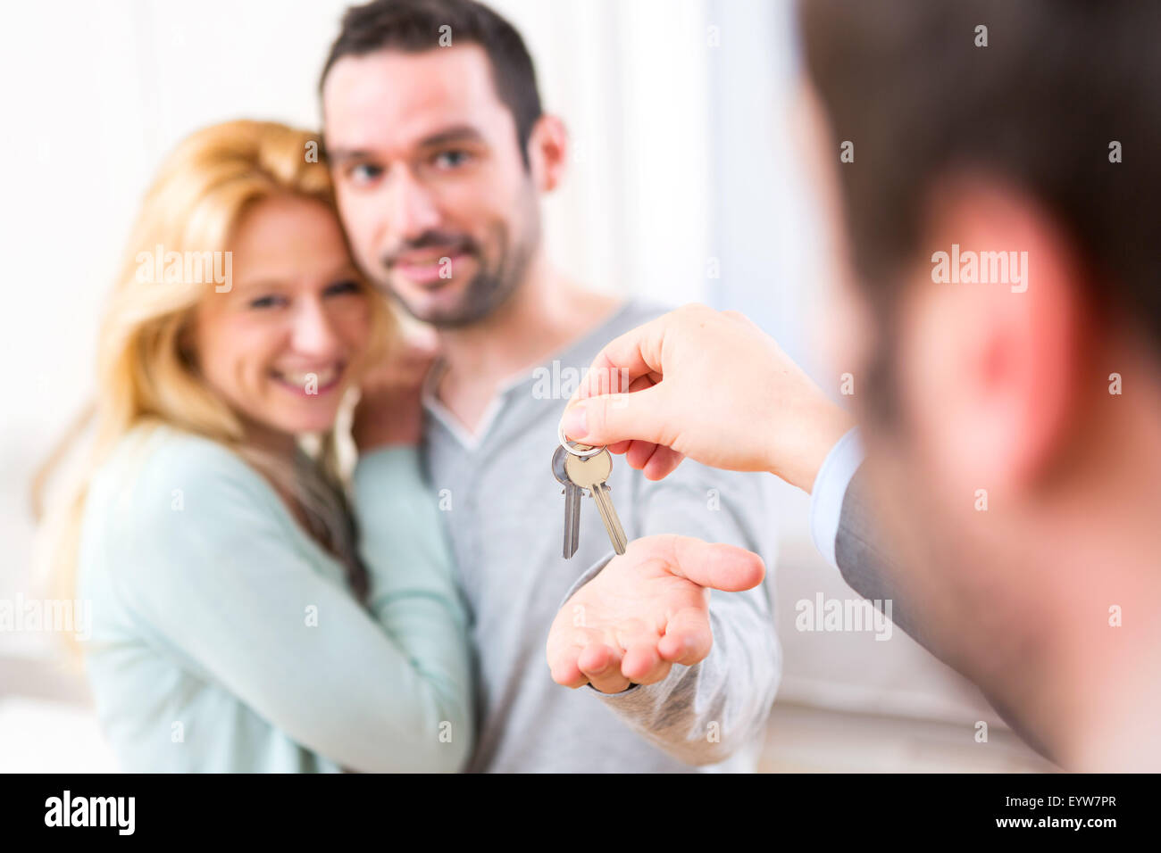 View of Real estate agent delivers keys of new house to young couple ...