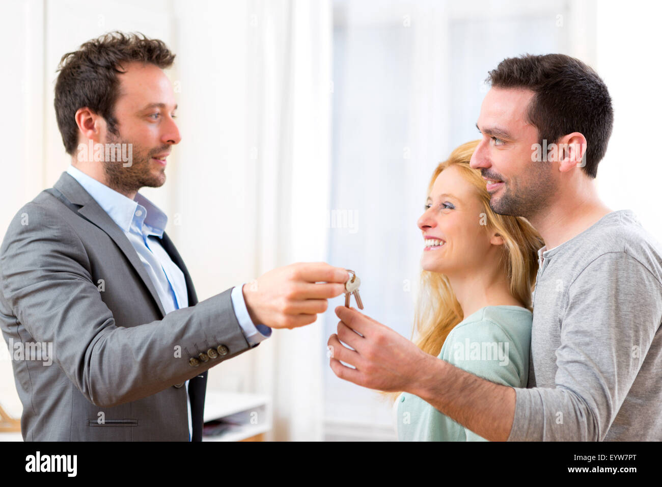 View of Real estate agent delivers keys of new house to young couple ...