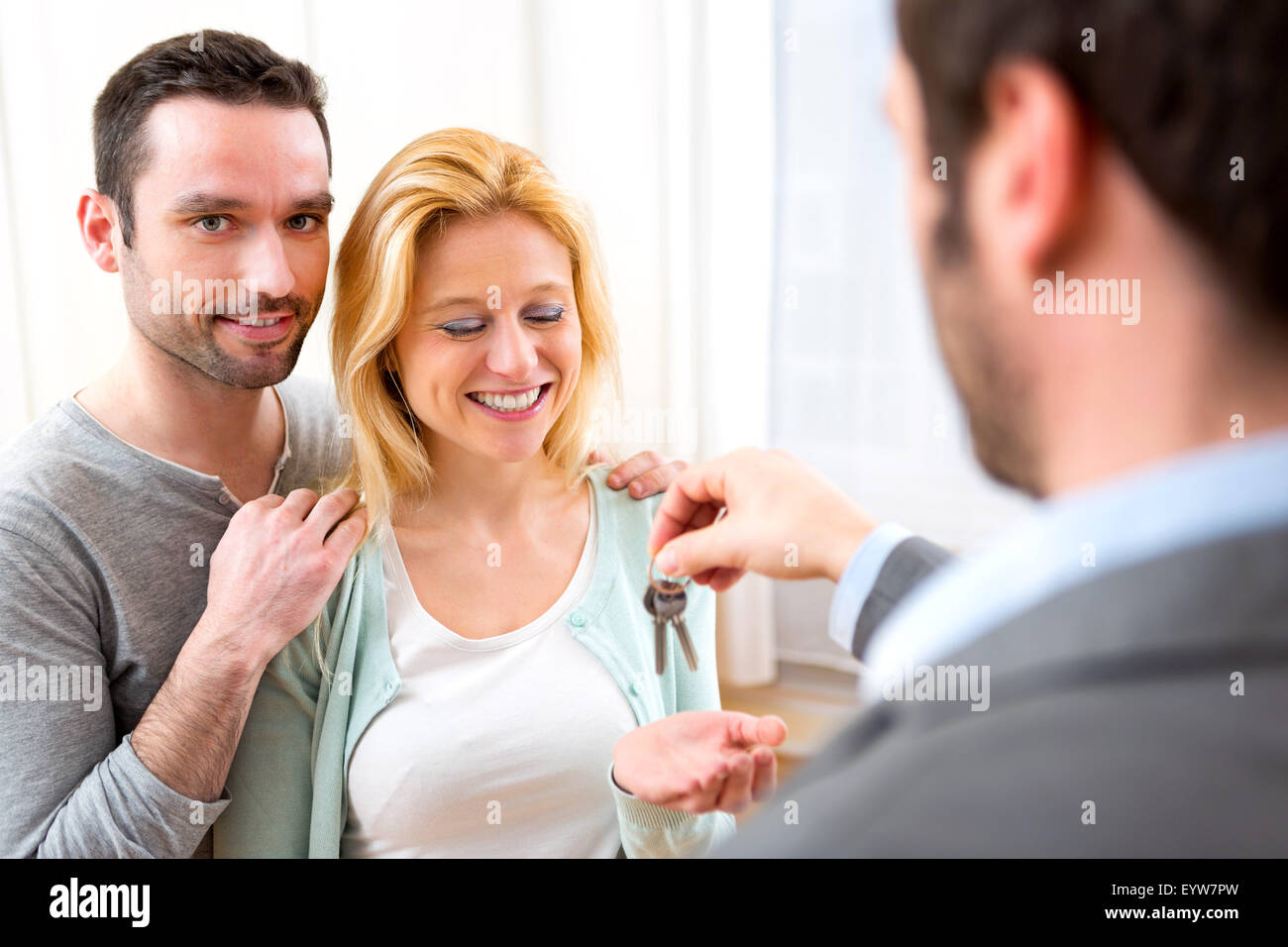 View of Real estate agent delivers keys of new house to young couple ...