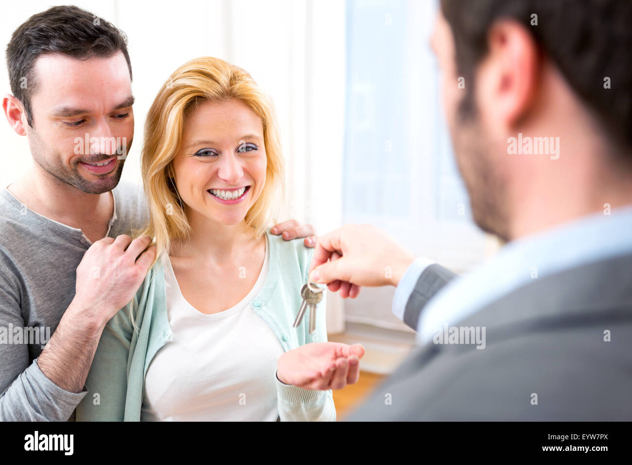 View of Real estate agent delivers keys of new house to young couple ...