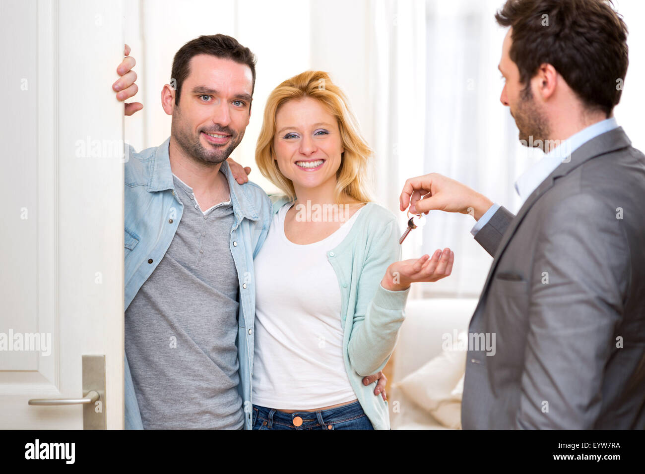 View of a Real estate agent delivers keys of new house to young couple ...